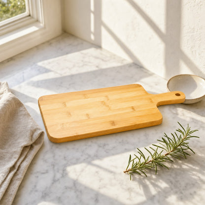 Bamboo cutting board with handle on a sunlit marble counter