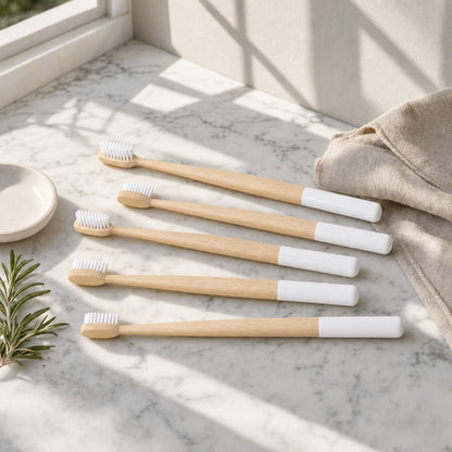 Five bamboo toothbrushes on a sunlit marble counter