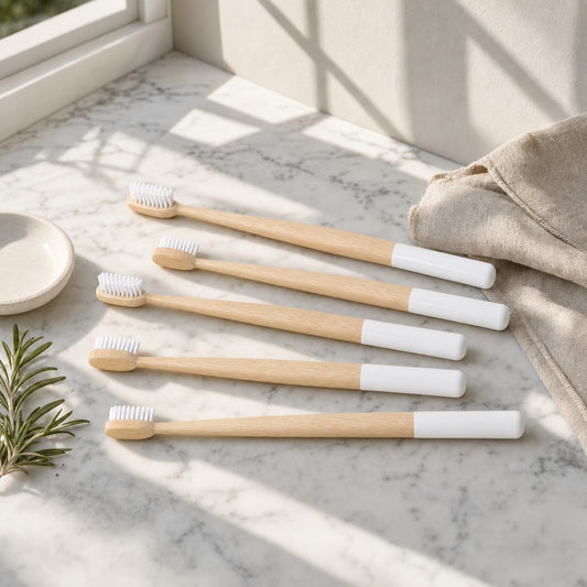 Five bamboo toothbrushes on a sunlit marble counter