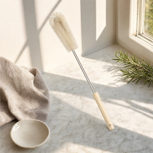 Long-handle bottle brush with wooden handle on a sunlit marble counter