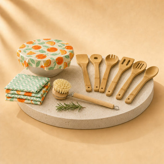 Kitchen swap kit with bamboo utensils, dish brush and beeswax wraps on a stone pedestal