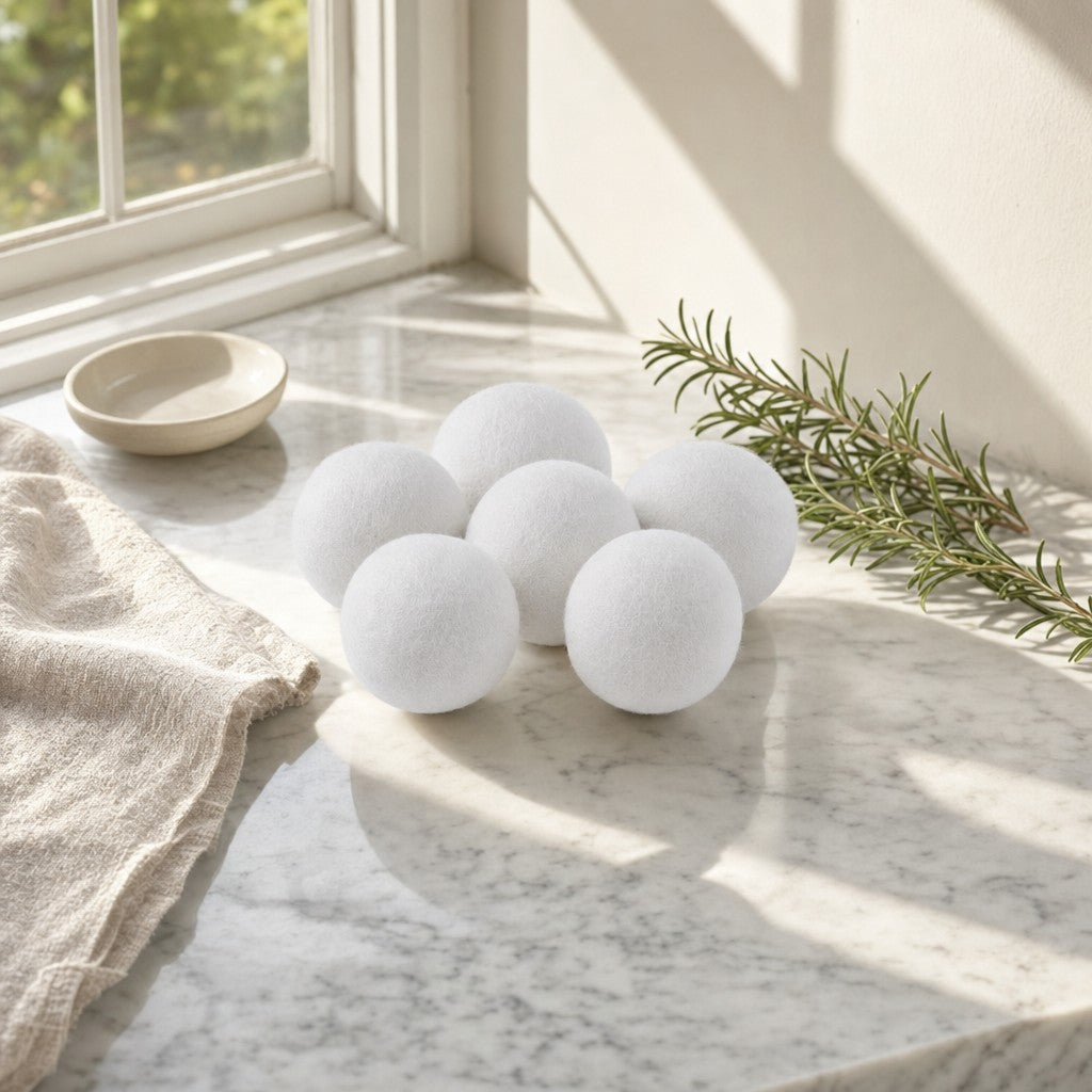 Six white wool dryer balls on a sunlit marble counter